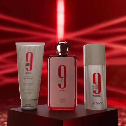 Bottles of shower gel, eau de parfum, and deodorant spray with Afnan 9PM Rebel branding on pedestal with a red laser firing background.