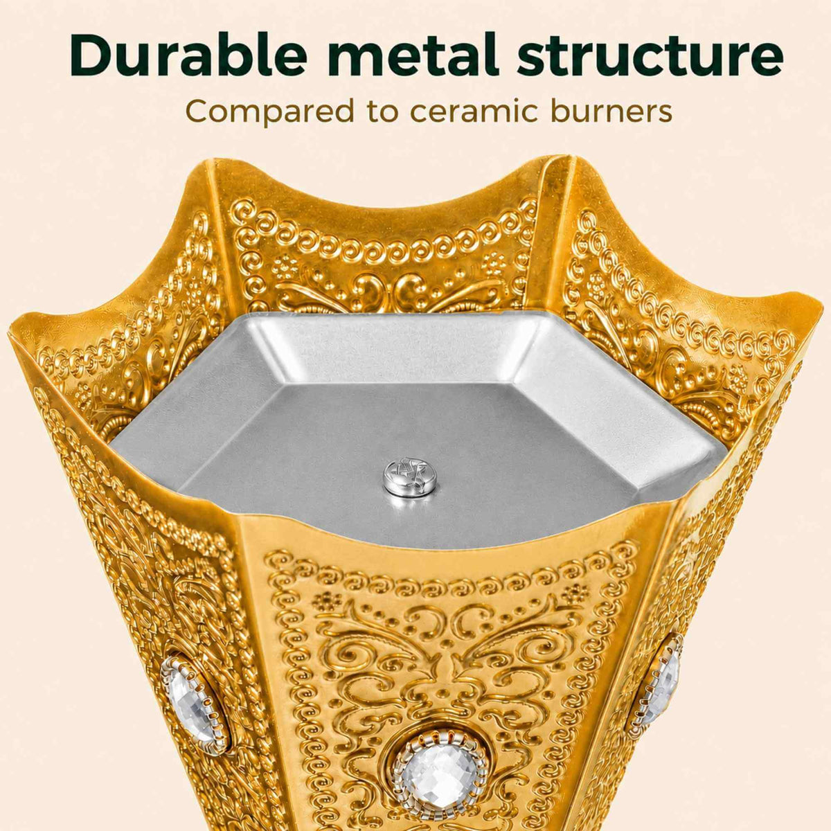 Top view of an ornate gold metal burner with embossed scrollwork and clear crystal accents, shown against a light beige background with the text 'Durable metal structure Compared to ceramic burners'.