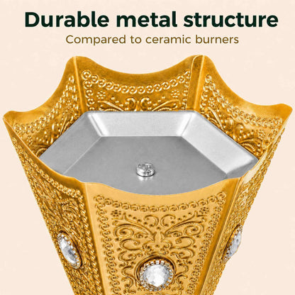 Top view of an ornate gold metal burner with embossed scrollwork and clear crystal accents, shown against a light beige background with the text 'Durable metal structure Compared to ceramic burners'.