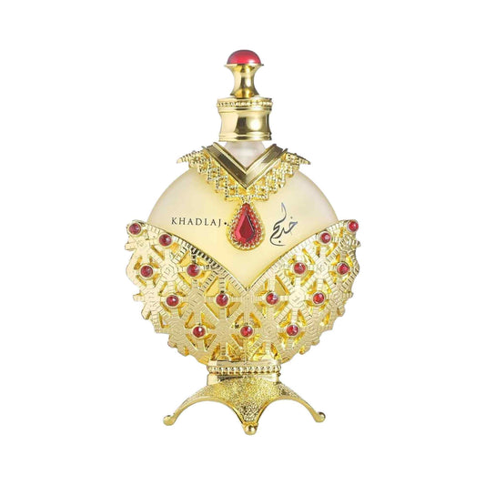An ornate perfume bottle with a cream-colored body, heavily decorated with gold filigree and accented with red gemstones, on a plain white background.
