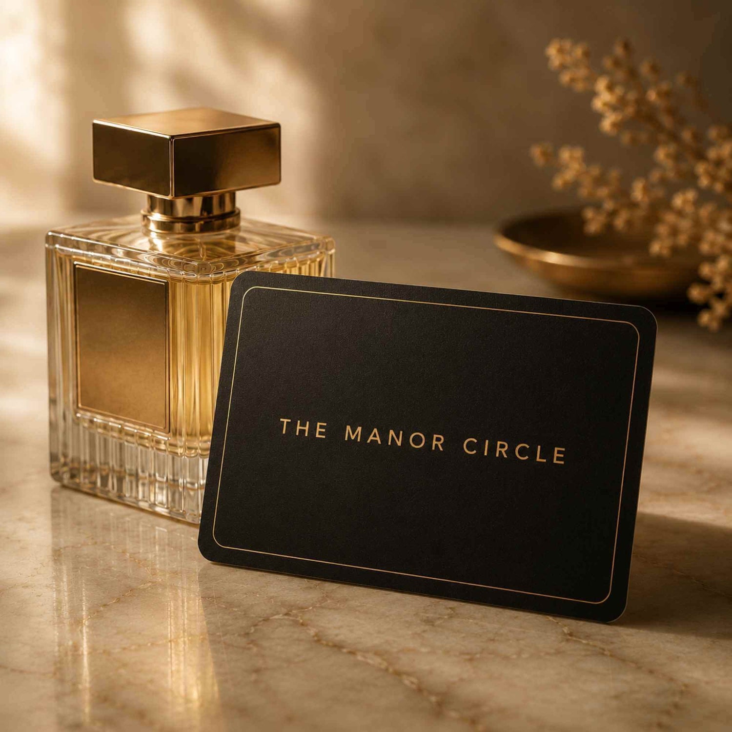 Perfume bottle with a card displaying 'The Manor Circle' on a marble surface.
